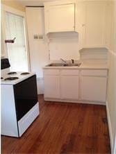 kitchen with a sink, light countertops, dark wood-type flooring, and electric range