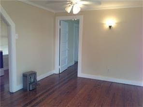 empty room featuring baseboards, a wood stove, ceiling fan, and wood finished floors
