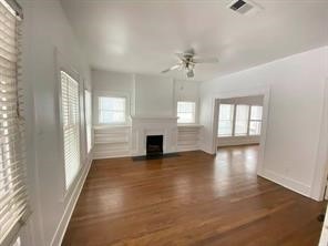 unfurnished living room with a fireplace, a ceiling fan, a healthy amount of sunlight, and wood finished floors