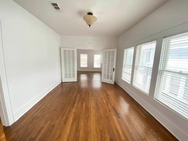 unfurnished room with baseboards, french doors, visible vents, and wood finished floors