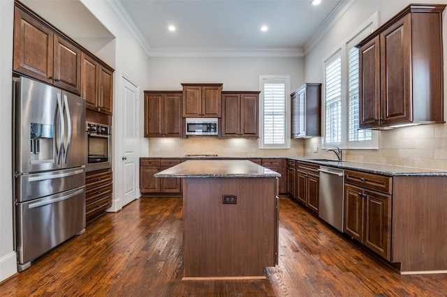 2110 Helsminster Dr, Dallas, TX 75201 - kitchen featuring appliances with stainless steel finishes, a kitchen island, a sink, dark wood-type flooring, and crown molding