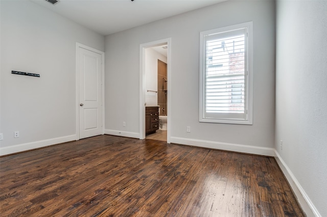 2110 Helsminster Dr, Dallas, TX 75201 - unfurnished bedroom featuring multiple windows, dark wood-style flooring, baseboards, and ensuite bath