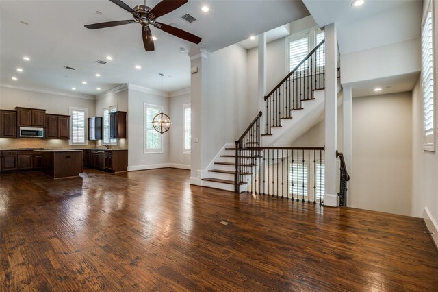 2110 Helsminster Dr, Dallas, TX 75201 - unfurnished living room featuring ceiling fan, plenty of natural light, dark wood-style flooring, a chandelier, and ornamental molding