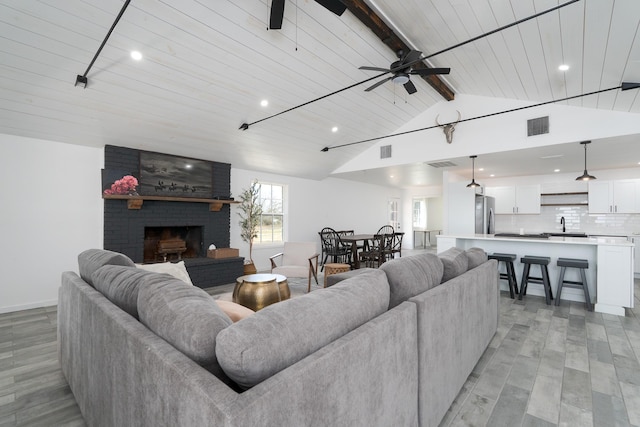 909 Crockett St, Santa Anna, TX 76878 - living room with light wood-type flooring, ceiling fan, lofted ceiling with beams, and a fireplace