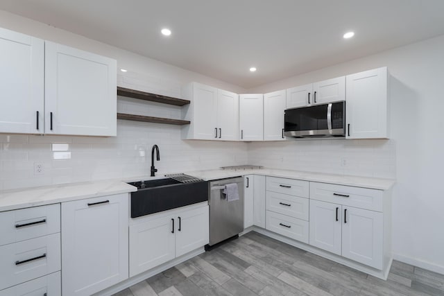 909 Crockett St, Santa Anna, TX 76878 - kitchen with light wood-type flooring, open shelves, a sink, stainless steel appliances, and decorative backsplash