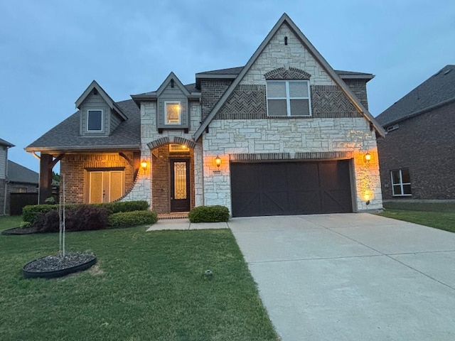 french provincial home with an attached garage, driveway, stone siding, roof with shingles, and a front yard