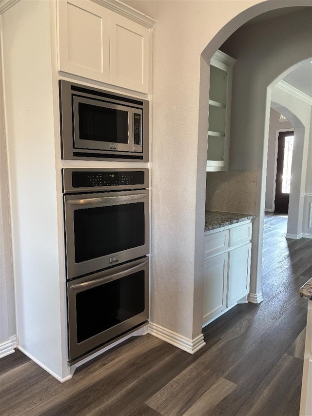 kitchen featuring baseboards, dark wood-style floors, and stainless steel appliances
