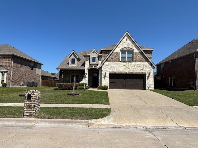 french country inspired facade featuring a front yard, central AC, an attached garage, stone siding, and concrete driveway