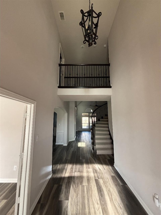 entryway with arched walkways, an inviting chandelier, high vaulted ceiling, and visible vents