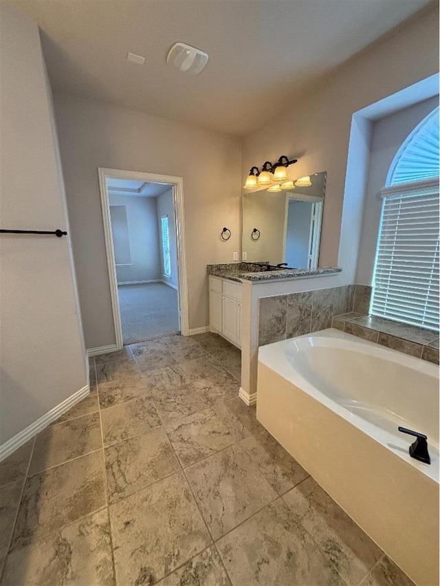 bathroom with a garden tub, vanity, baseboards, and visible vents