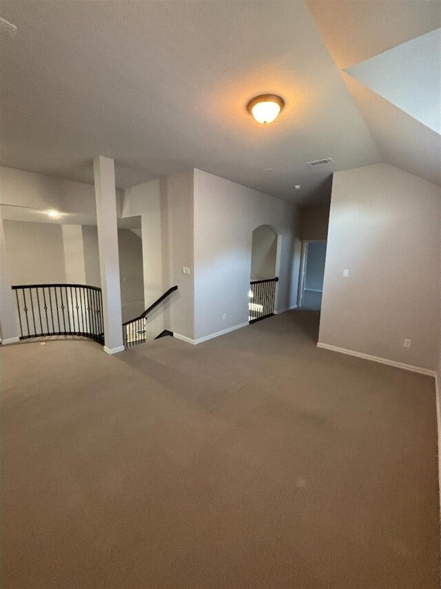 carpeted spare room featuring baseboards, lofted ceiling, and visible vents