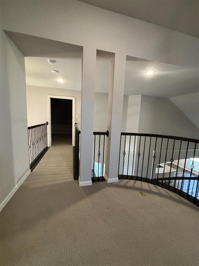 hallway with an upstairs landing, baseboards, and carpet floors