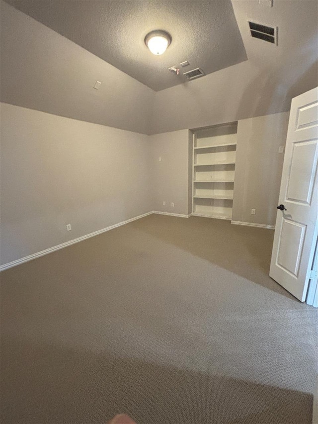 interior space featuring built in features, a textured ceiling, visible vents, carpet floors, and baseboards