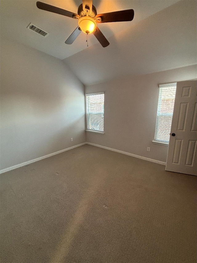 carpeted spare room with visible vents, baseboards, a ceiling fan, and vaulted ceiling