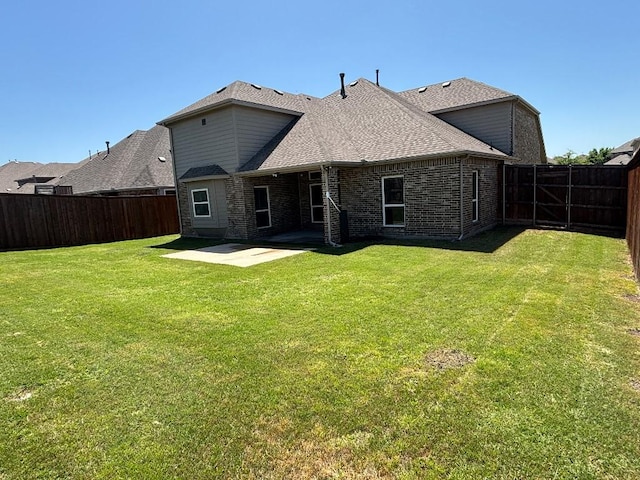back of house with brick siding, a fenced backyard, a patio area, and a lawn