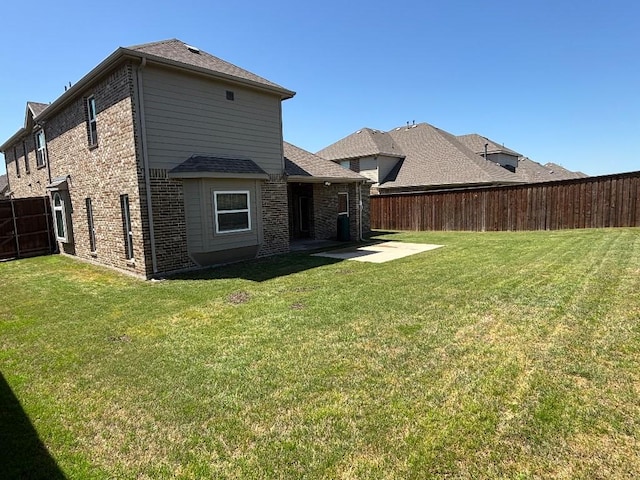 rear view of house featuring a yard, a patio area, fence, and brick siding