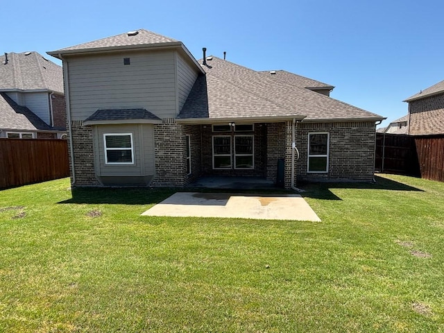 rear view of property with a patio, a yard, a fenced backyard, and roof with shingles