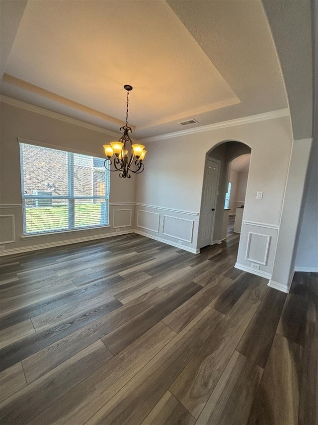 unfurnished dining area featuring visible vents, a raised ceiling, arched walkways, an inviting chandelier, and a decorative wall