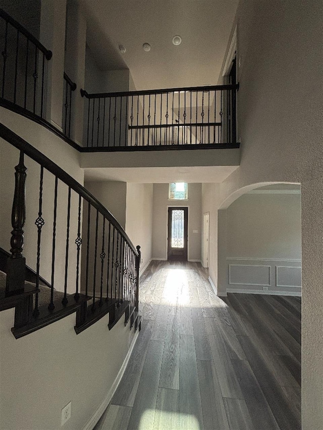 foyer with stairs, a high ceiling, baseboards, and wood finished floors