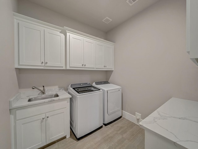 8505 Tierra Ct, Benbrook, TX 76126 - washroom with visible vents, a sink, washing machine and dryer, light wood-style floors, and cabinet space