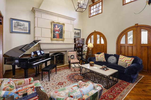 3636 Amherst Ave, University Park, TX 75225 - living room featuring a towering ceiling, a notable chandelier, a fireplace with raised hearth, and wood finished floors