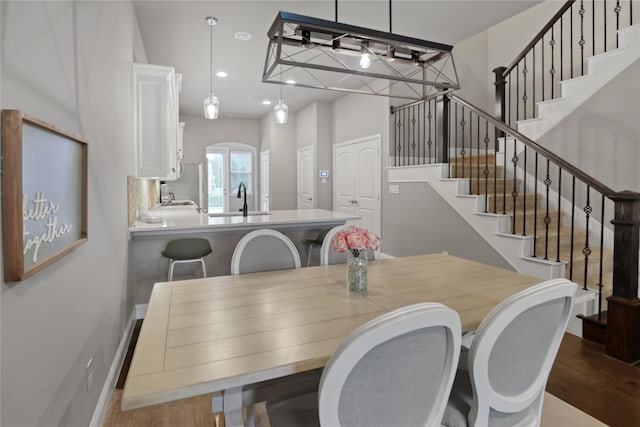 dining room featuring recessed lighting, stairway, wood finished floors, arched walkways, and baseboards