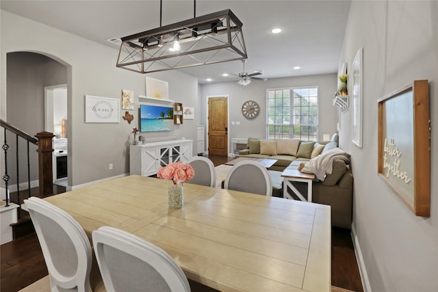 dining area featuring arched walkways, dark wood-style flooring, baseboards, recessed lighting, and stairway