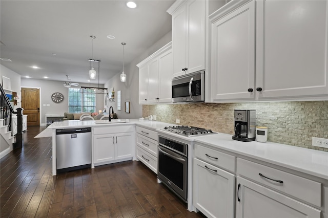kitchen featuring white cabinets, appliances with stainless steel finishes, open floor plan, and a sink