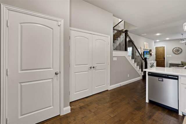 kitchen with stainless steel dishwasher, light countertops, white cabinets, baseboards, and dark wood-type flooring