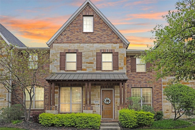 multi unit property featuring stone siding, a standing seam roof, brick siding, and metal roof
