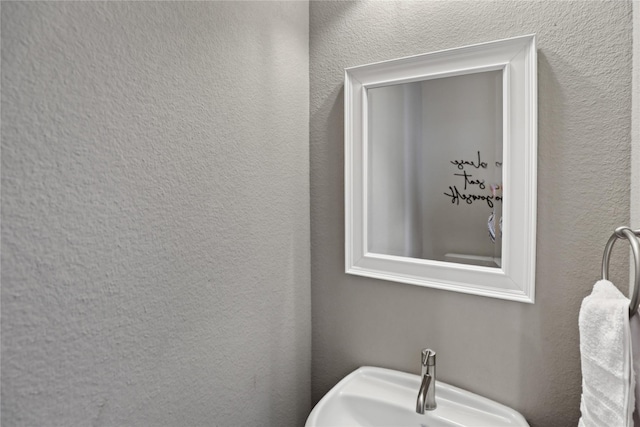 bathroom featuring a textured wall and a sink