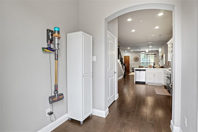 hall featuring baseboards, arched walkways, recessed lighting, and dark wood finished floors