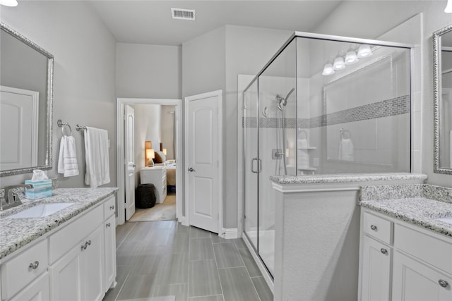 ensuite bathroom featuring visible vents, a sink, ensuite bath, two vanities, and a stall shower