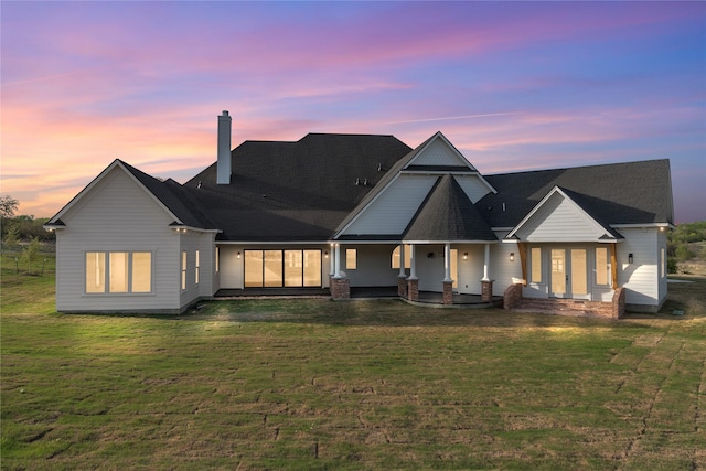 401 Lution Dr, Weatherford, TX 76087 - back of house at dusk with a chimney, a lawn, and covered porch