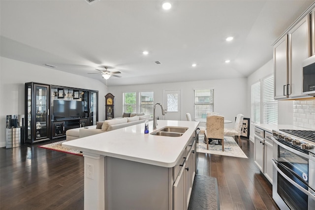 kitchen with dark wood-type flooring, double oven range, light countertops, a sink, and backsplash