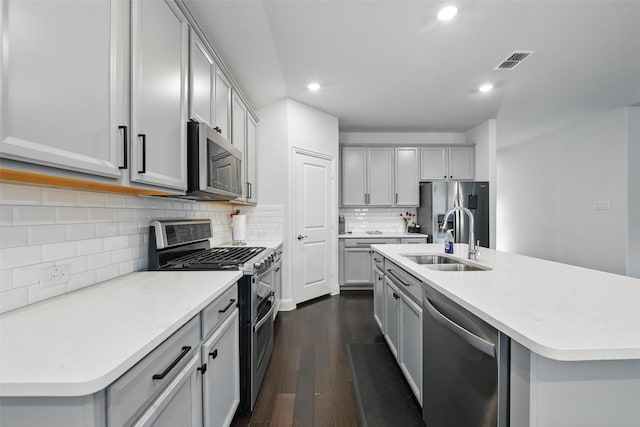 kitchen featuring visible vents, a sink, stainless steel appliances, dark wood-type flooring, and gray cabinets