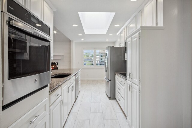 5111 Cimmaron Cir, Parker, TX 75002 - kitchen featuring a sink, appliances with stainless steel finishes, a skylight, white cabinets, and light marble finish floors