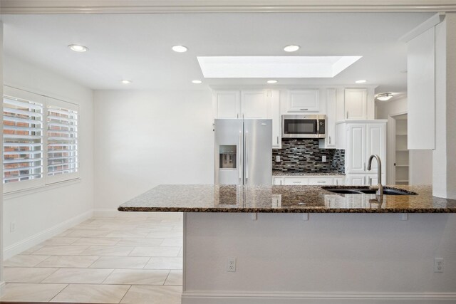 5111 Cimmaron Cir, Parker, TX 75002 - kitchen featuring stainless steel appliances, a skylight, a sink, baseboards, and a kitchen bar
