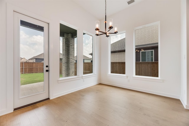 interior space featuring an inviting chandelier, plenty of natural light, wood finished floors, and visible vents
