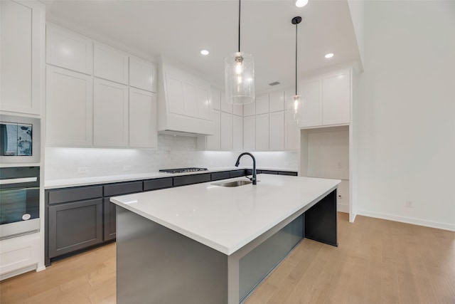 kitchen featuring gray cabinets, tasteful backsplash, a sink, light wood-style floors, and oven