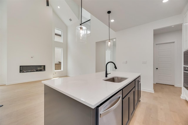 kitchen with stainless steel dishwasher, a sink, high vaulted ceiling, light countertops, and light wood finished floors