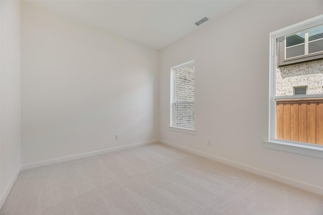 unfurnished room with a healthy amount of sunlight, baseboards, light colored carpet, and visible vents