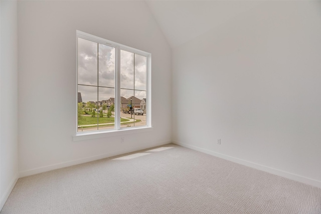 carpeted empty room featuring baseboards and lofted ceiling