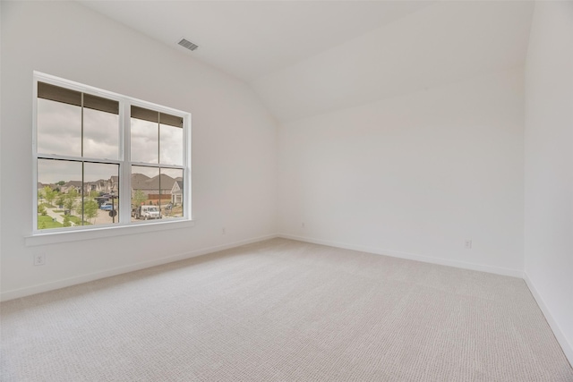 unfurnished room with baseboards, carpet flooring, lofted ceiling, and visible vents