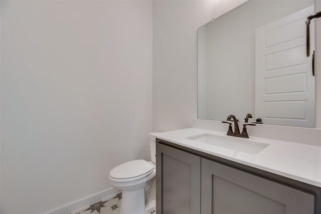 half bath with toilet, baseboards, and vanity