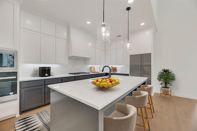 kitchen with light wood-style floors, light countertops, stainless steel appliances, decorative backsplash, and gray cabinetry