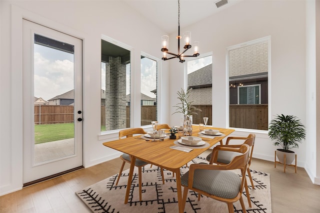 dining space featuring visible vents, a notable chandelier, a wealth of natural light, and light wood-style flooring