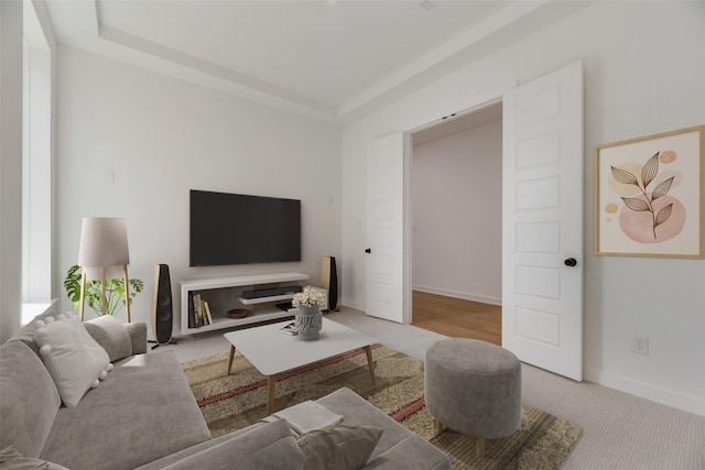carpeted living room with baseboards and a raised ceiling