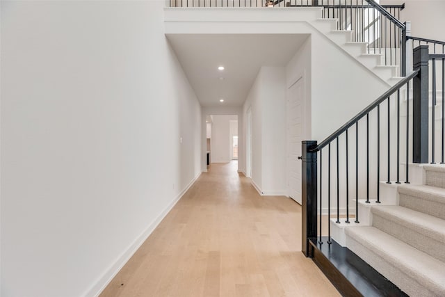 hall featuring recessed lighting, baseboards, light wood-style flooring, and stairs
