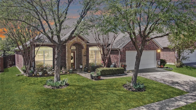 view of front of home with a shingled roof, an attached garage, brick siding, a front lawn, and driveway
